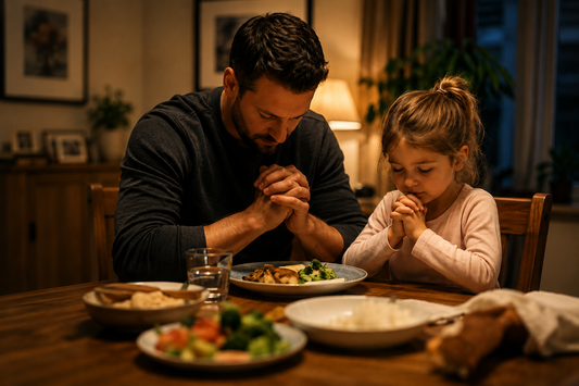 Christian father and young daughter praying together before dinner at home
